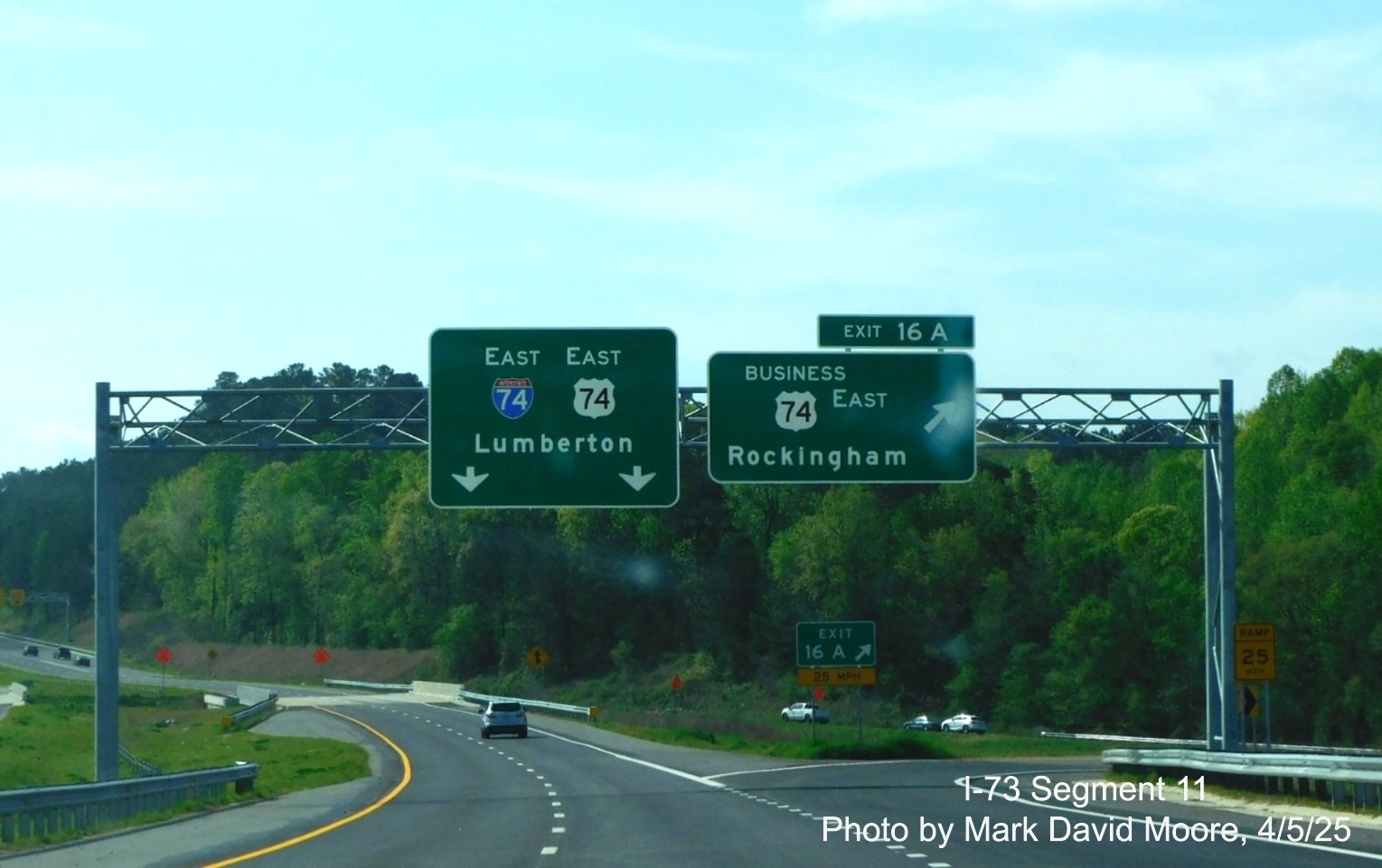 Image of overhead signs at the Business 74 East exit with the first I-74/US 74
pull through sign by Mark David Moore, April 2025