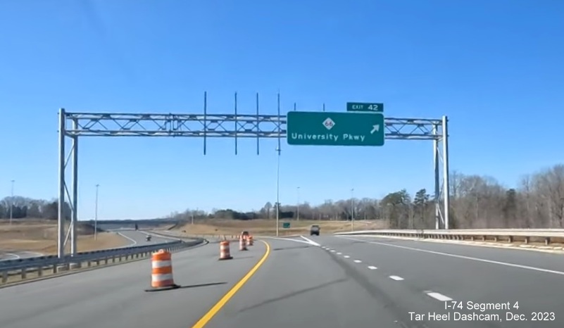 Image of overhead ramp sign for NC 66/University Parkway exit on NC 74 (Future I-74) West after 
        segment to US 52 opened, from video by Tar Heel Dashcam, December 2023