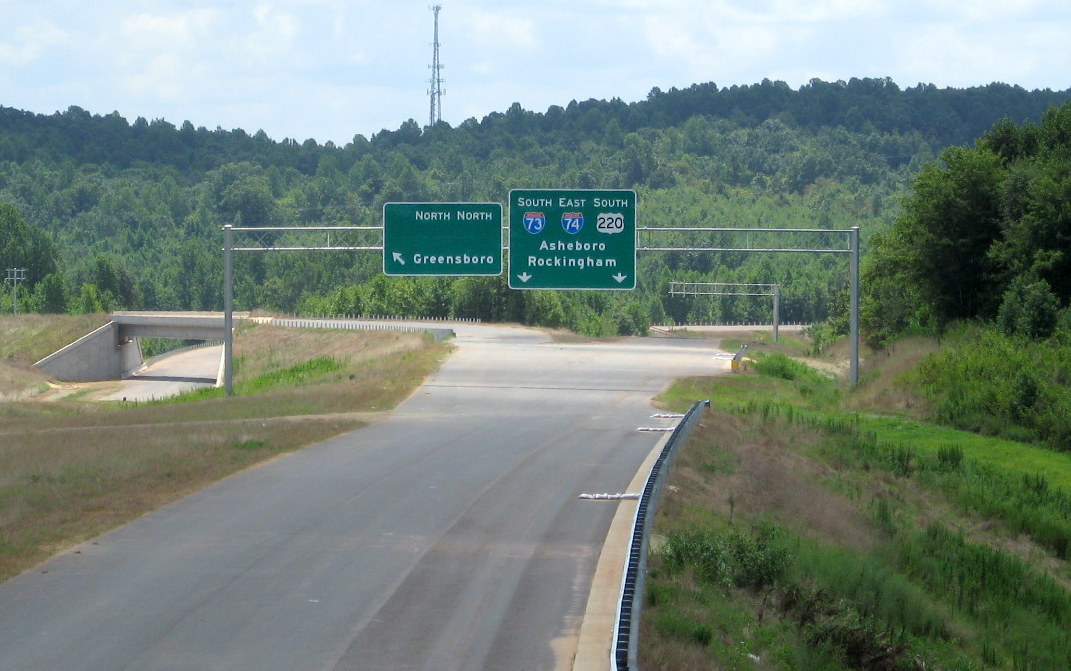 Photo of view south of Heath Dairy Road Bridge showing overhead signs being 
installed at US 220 interchange on future I-74 freeway near Randleman, July 2012