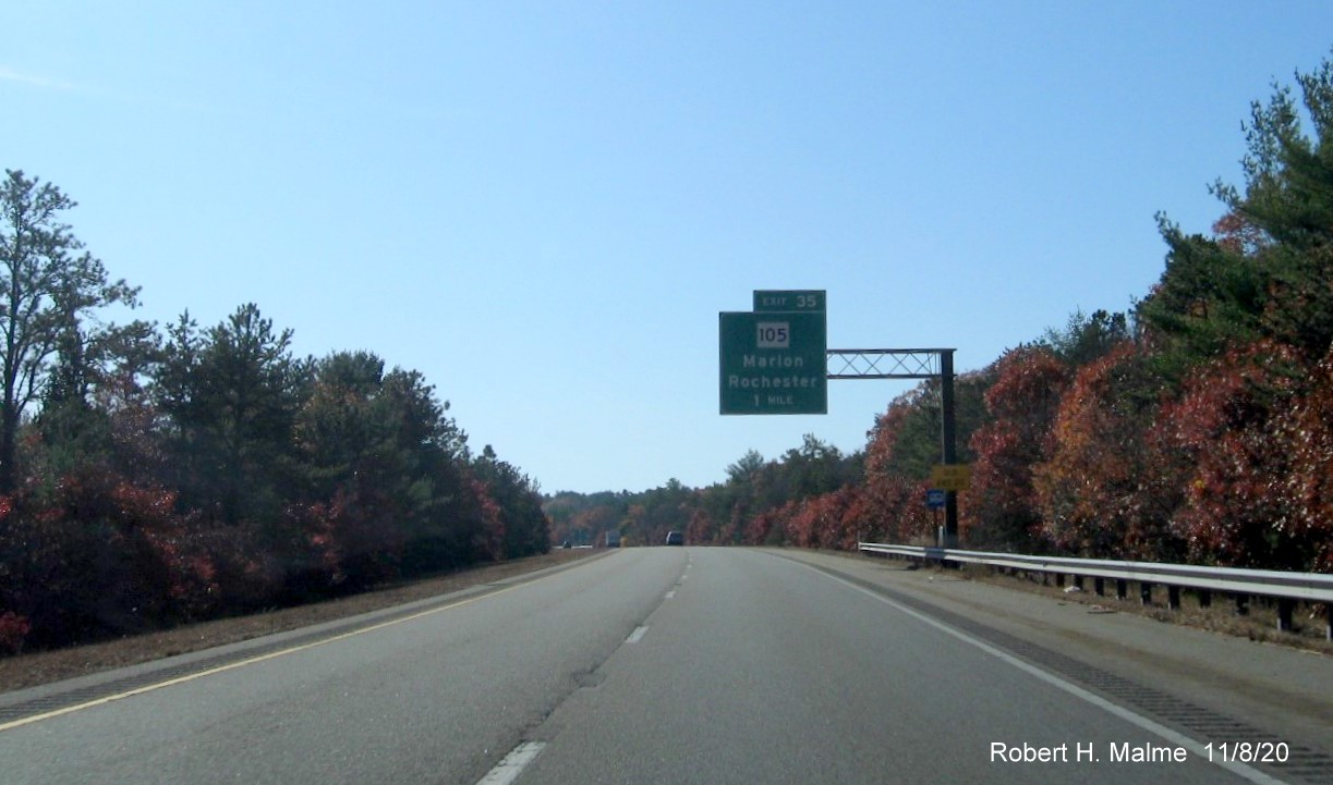 Image of 1-mile advance overhead sign for MA 105 exit with newly placed milepost based exit number and yellow old exit number sign on support post on I-195 West in Wareham, November 2020