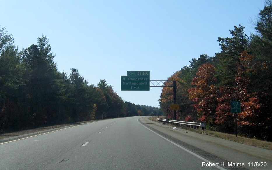 Image of 1-mile advance overhead sign for Rochester/Mattapoisett exit with new milepost based exit number and yellow old exit sign on support post on I-195 West in Mattapoisett, November 2020