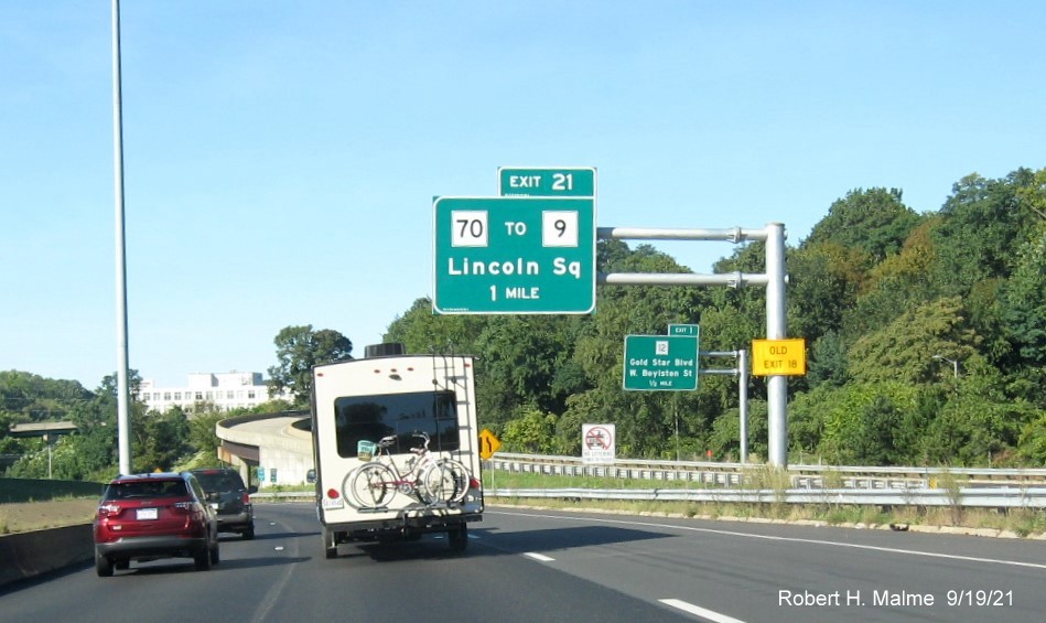 Image of recently placed 1 mile advance overhead sign for MA 70 to MA 9 exit with new milepost based exit number and yellow Old Exit 18 advisory sign on support on I-290 West in Worcester, September 2021