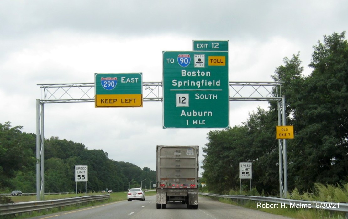 Image of 1 mile advance overhead sign for I-90/Massachusetts Turnpike and MA 12 exit with new milepost based exit number and yellow Old Exit 7 advisory sign on right support on I-395 North in Auburn, August 2021