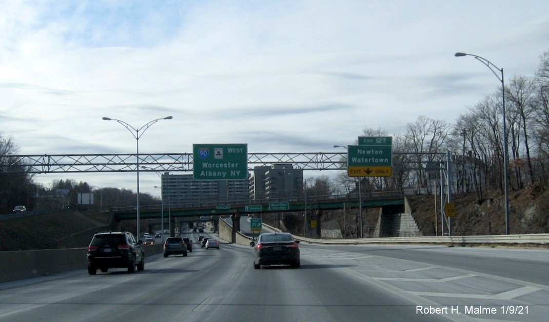 Image of overhead ramp sign for Newton/Watertown exit with new milepost based exit number and yellow Old Exit 17 sign on support post on I-90/Mass Pike West in Newton, January 2021