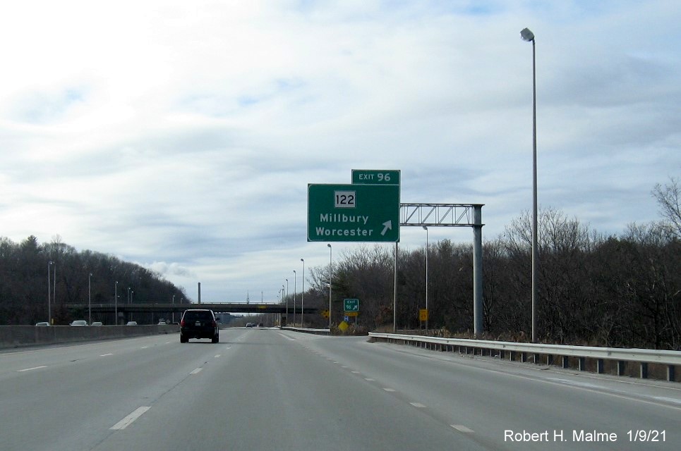 Image of overhead ramp sign for MA 122 exit with new milepost based exit number and gore sign with new number and yellow Old Exit 11 sign below on I-90/Mass Pike West in Millbury, January 2021