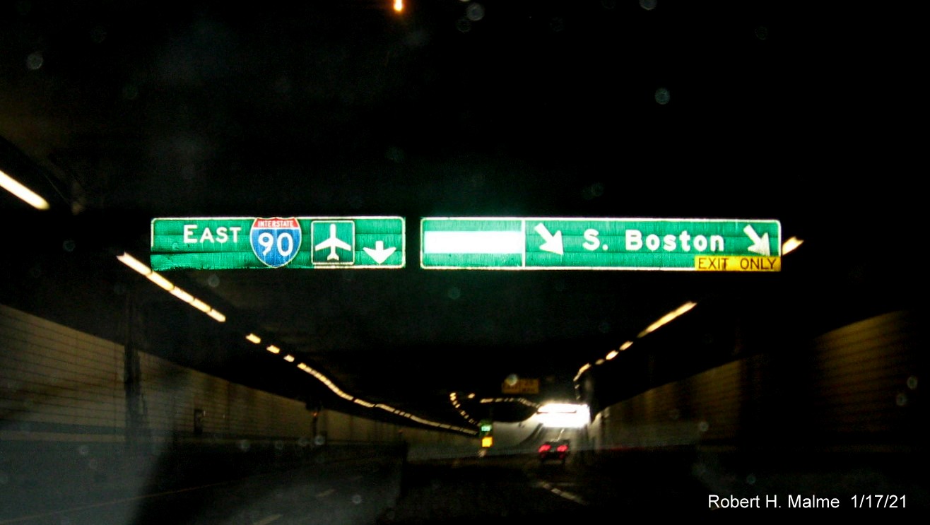 Image of overhead signs mounted to ceiling of tunnel under Fort Point Channel for South Boston exit with new milepost based exit number on I-90/Massachusetts Turnpike in South Boston, January 2021