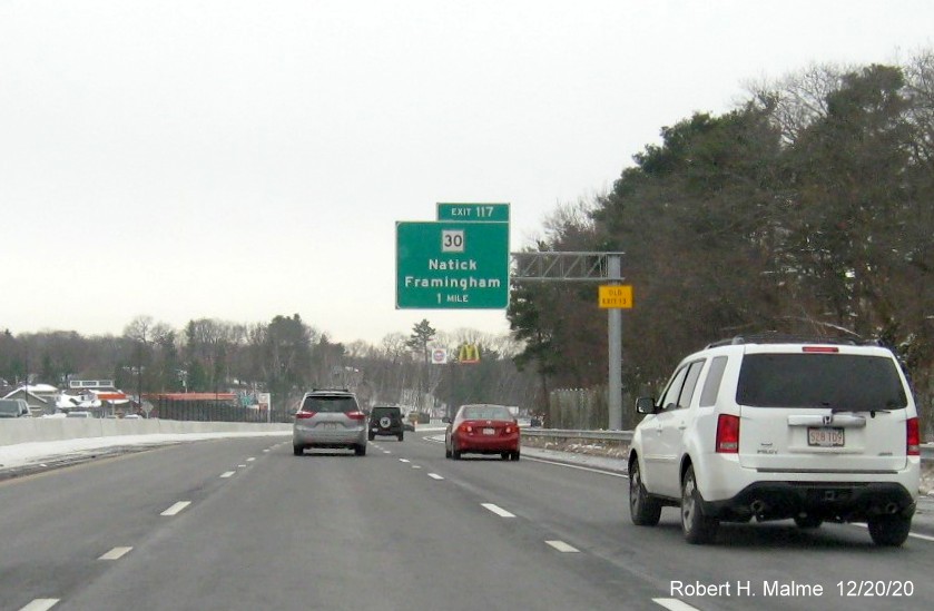 Image of 1-mile advance overhead sign for MA 30 exit with new milepost based exit number and yellow old exit number sign on support post on I-90/Mass Pike West in Natick, December 2020