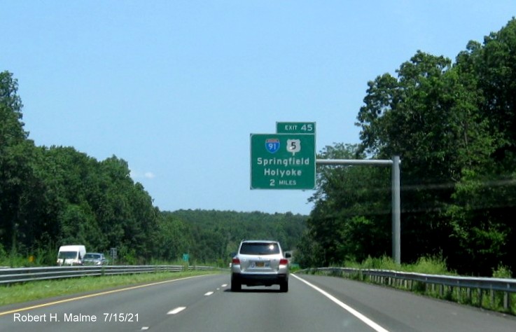 Image of 2 miles advance overhead sign for I-91/US 5 exit with new milepost based exit number on I-90/Mass Pike East in West Springfield, July 2021