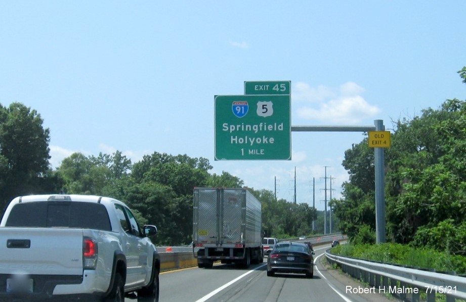 Image of 1 mile advance sign for I-91/US 5 exit with new milepost based exit number and yellow Old Exit 4 advisory sign on support on I-90/Mass Pike West in Springfield, July 2021