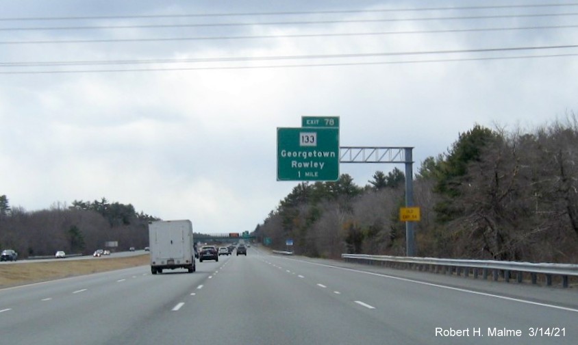 Image of 1 mile advance overhead sign for MA 133 exit with new milepost based exit number and yellow Old Exit 54 advisory sign on support on I-95 South in Georgetown, March 2021 
