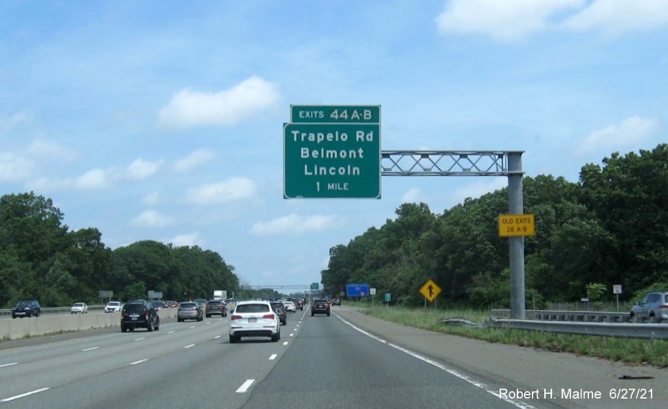 Image of 1 Mile advance overhead sign for Trapelo Road exit with new milepost based exit numbers and yellow Old Exits 28 A-B advisory sign on support on I-95/MA 128 North in Waltham, June 2021