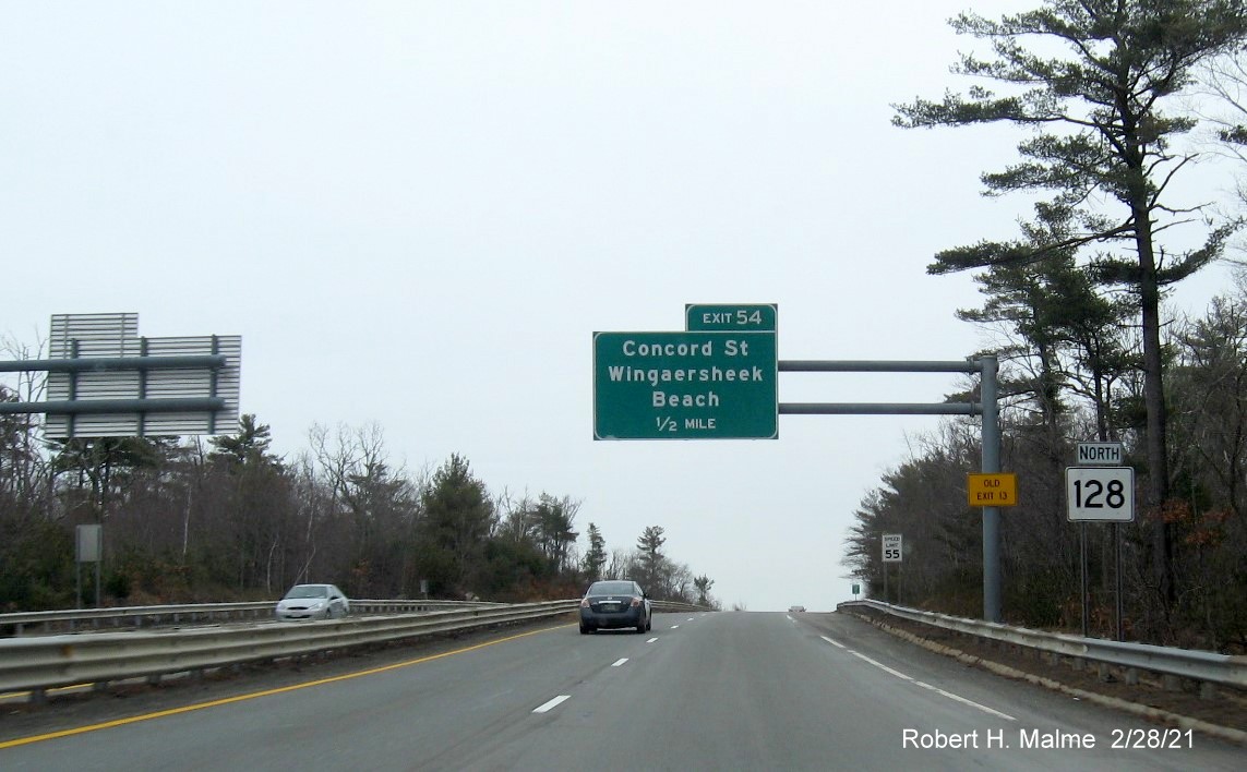 Image of 1/2 mile advance overhead sign for Concord Street exit with new milepost based exit number and yellow old exit number sign on support post on MA 128 North in Gloucester, February 2021