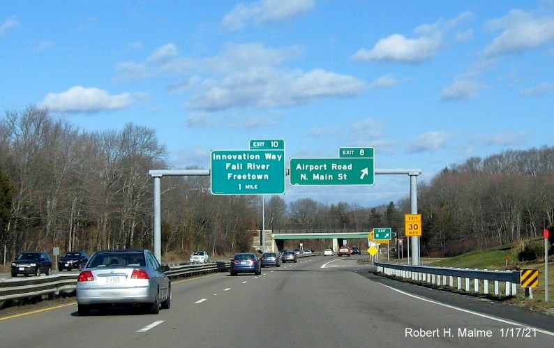 Image of overhead signage at Airport Road/North Main Street exit with new milepost based exit number and gore sign with new number and yellow Old Exit 8A sign below on MA 24 North in Fall River, January 2021