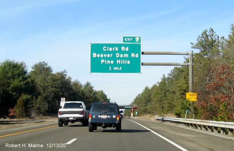 Image of 1-mile advance overhead sign for Clark Road exit with new milepost based exit number and yellow old exit number sign on support post on MA 3 North in Plymouth, December 2020