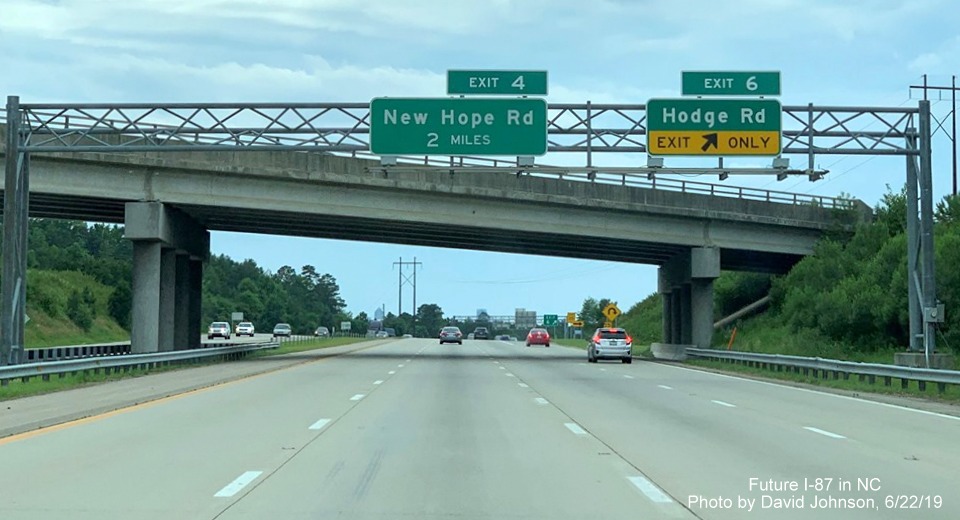 Image of overhead signs with new I-87 exit number tabs at Hodge Road exit on I-87 South, US 64/264 West in Knightdale, by David Johnson