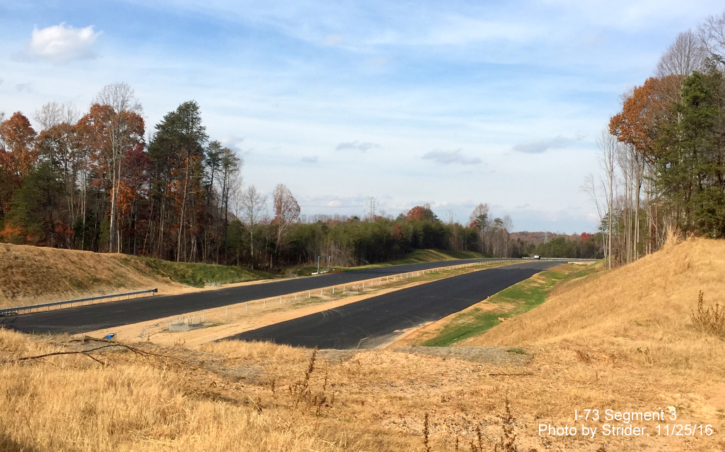 Image of view looking north from Alcorn Road overpass showing progress in installing guardrails and signs on Future I-73
            roadway, from Strider