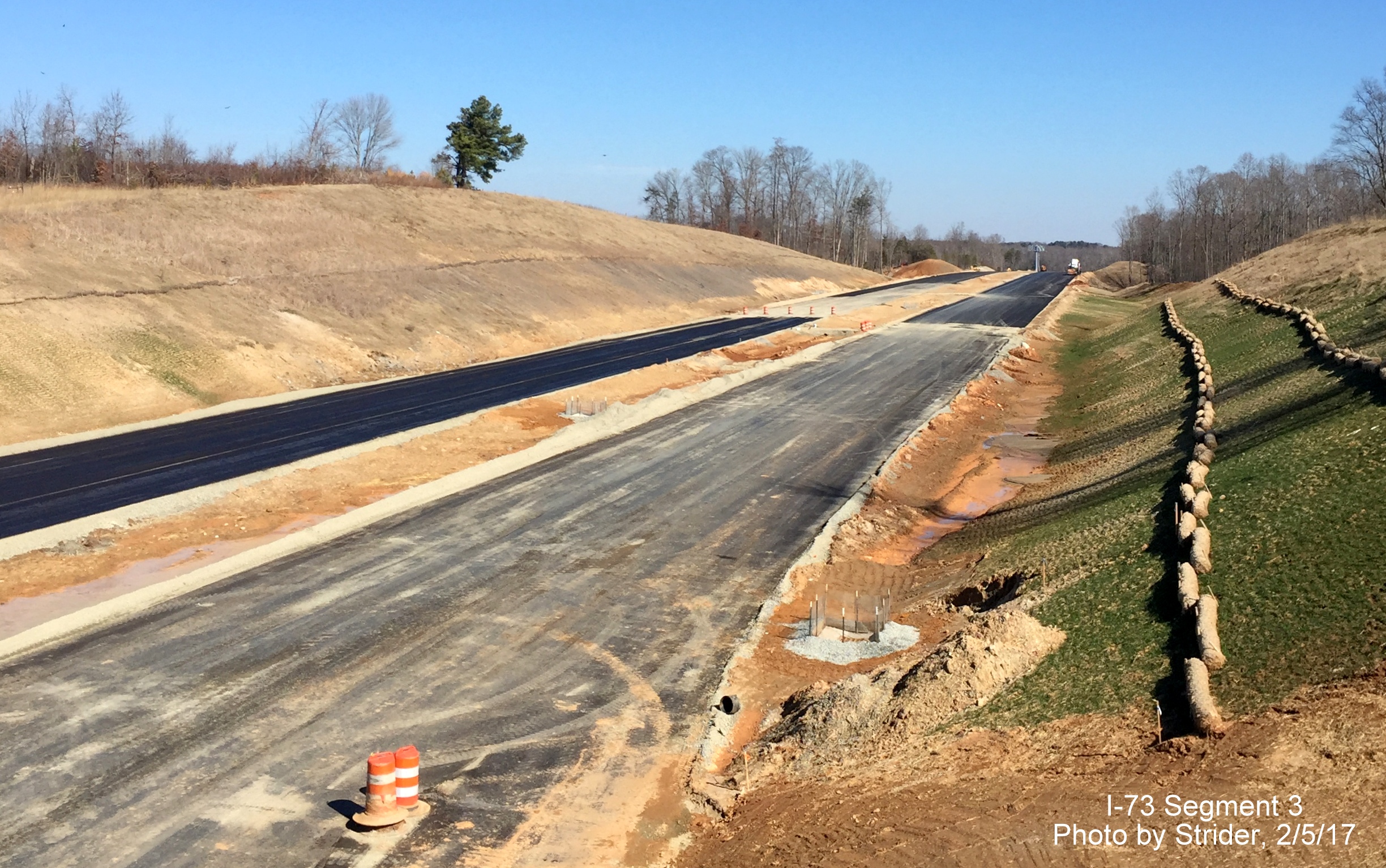 Image looking north from Bunch Road bridge over future I-73 lanes showing progress in paving, from Strider