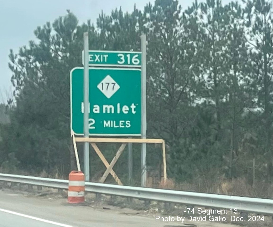 Image of new sign supports for NC 177 exit going up in front of old sign on 
	  US 74 (Future I-74) East in Hamlet, by David Gallo, December 2024
