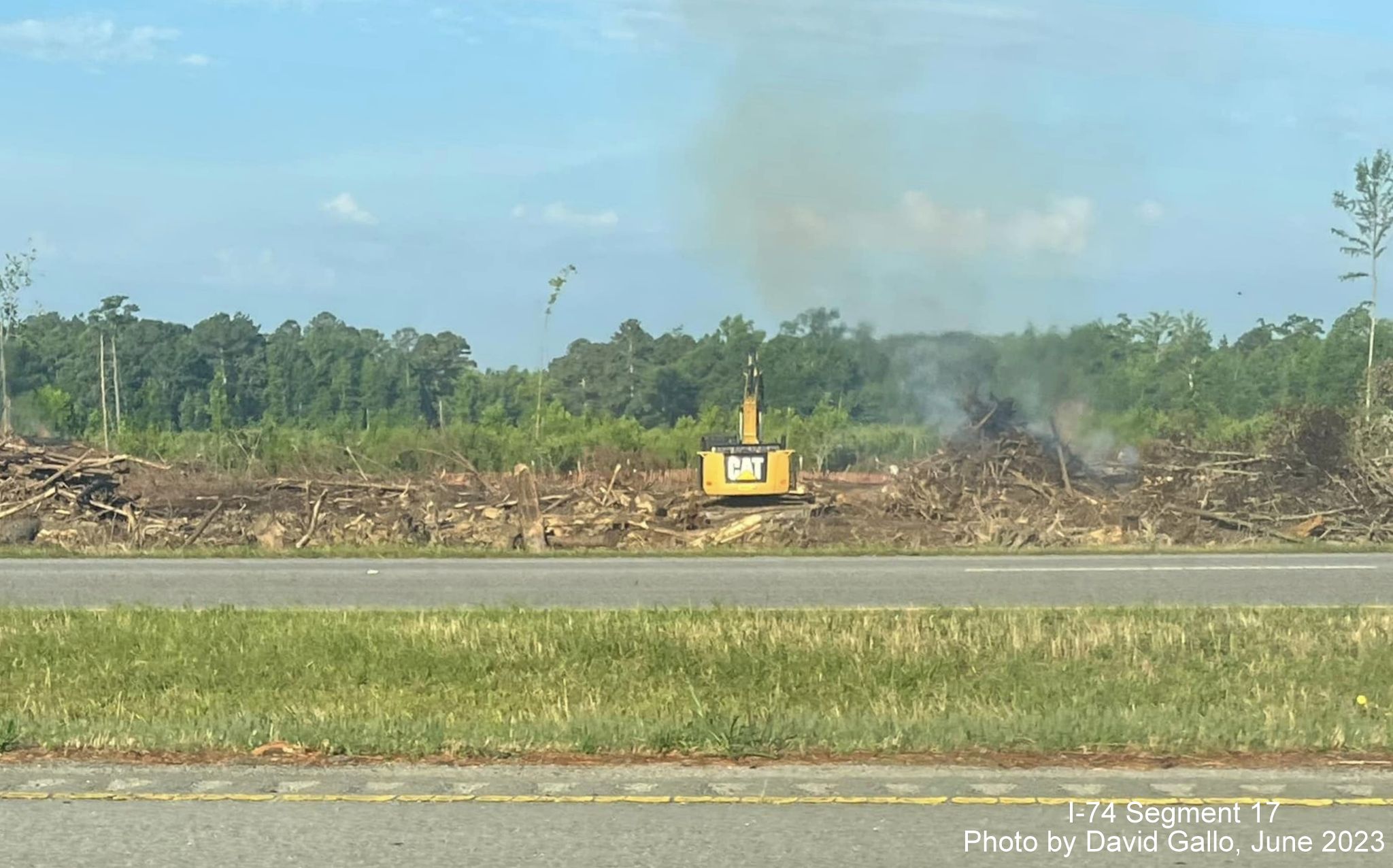 Image of brush being cleared and burned in area surrounding future interchange with US 74 
       (Future I-74) and NC 72/130, by David Gallo, June 2023