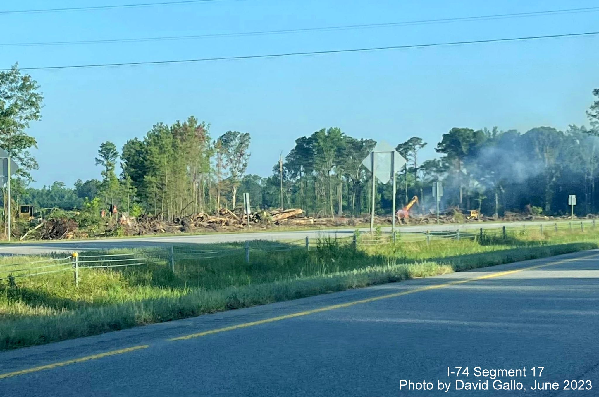 Image of brush being cleared and burned in area surrounding future interchange with US 74 
       (Future I-74) and NC 72/130, by David Gallo, June 2023