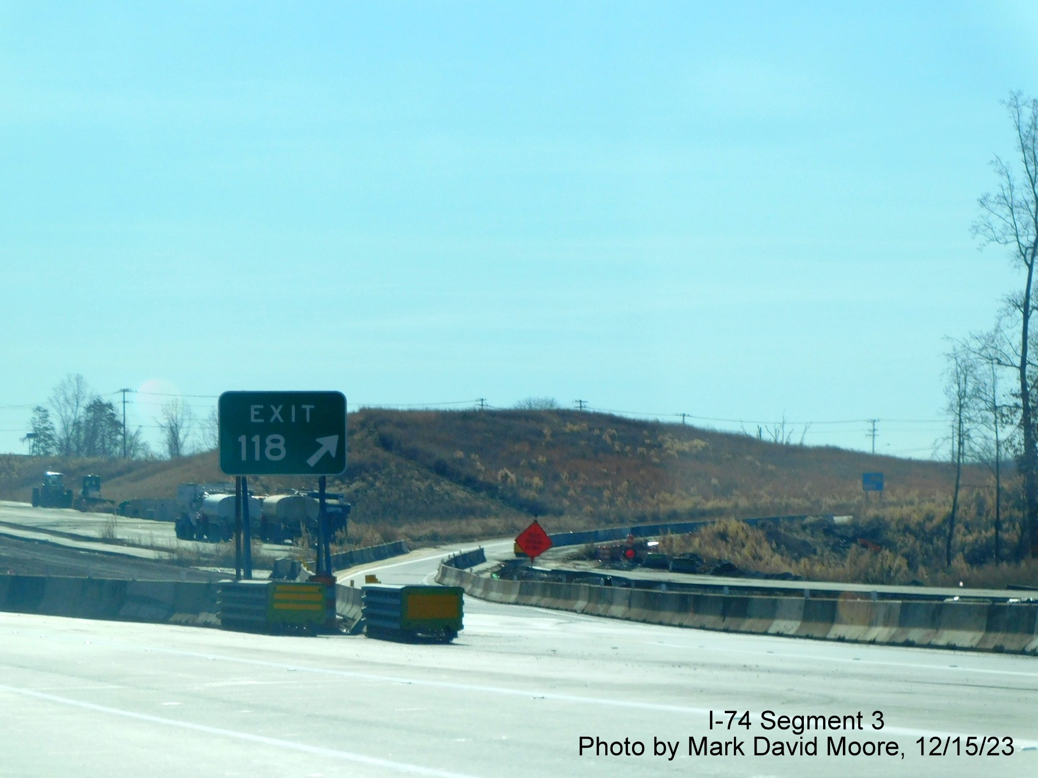 Image of gore sign for current NC 65 exit prior to completed Winston-Salem Northern Beltway 
        interchange, showing crossing of future eastbound lanes, by Mark David Moore, December 2023
