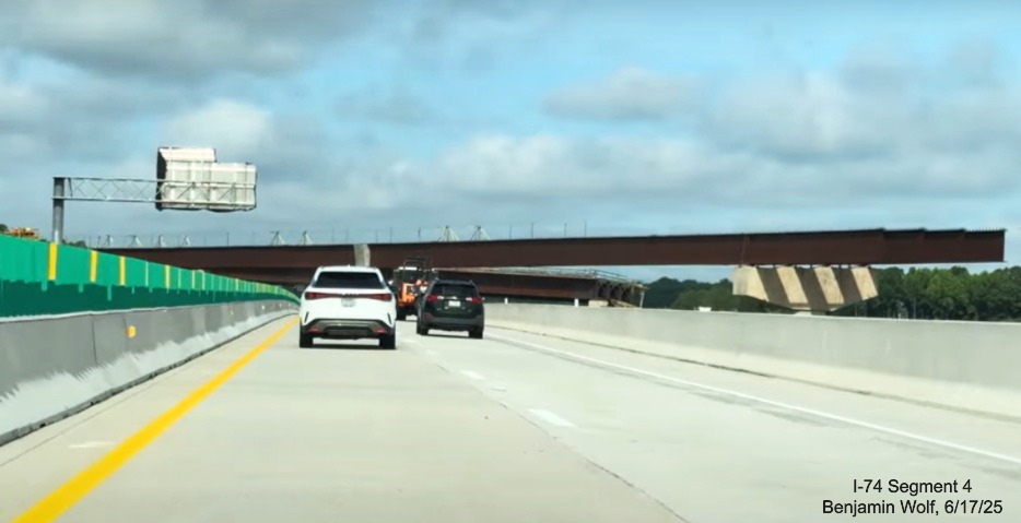 Image of traffic on I-40 West heading under flyover ramp for future ramp to
	  I-74 East/ Winston-Salem Northern Beltway, screen grab from Benjamin Wolf video, June 2025