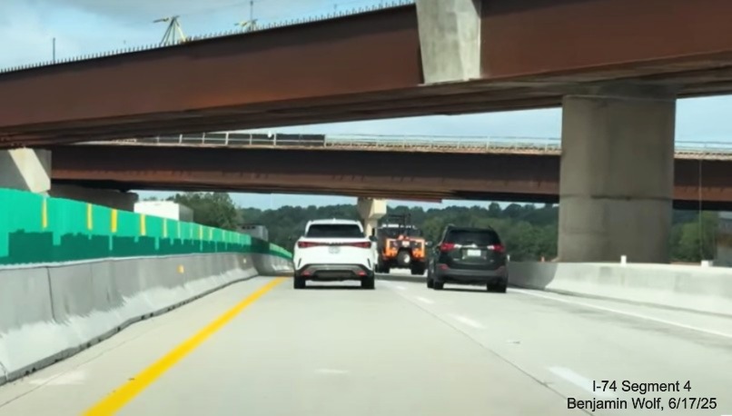 Image of traffic on I-40 West heading under two of the flyover ramps for the future 
	  I-74 East/ Winston-Salem Northern Beltway interchange, screen grab from Benjamin Wolf video, June 2025