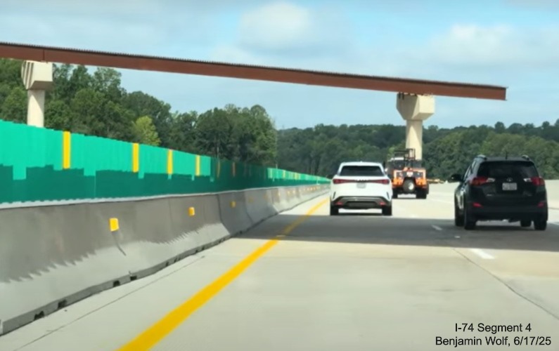 Image of traffic on I-40 West heading under flyover ramp for future ramp to
	  I-74 East/ Winston-Salem Northern Beltway, screen grab from Benjamin Wolf video, June 2025