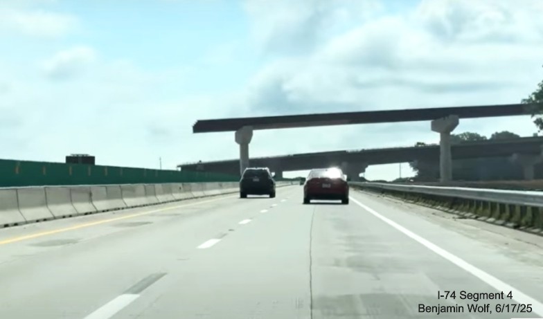 Image of traffic on I-40 East heading toward partially completed flyover ramps in
	  the I-74 / Winston-Salem Northern Beltway interchange work zone, screen grab from Benjamin Wolf video, June 2025