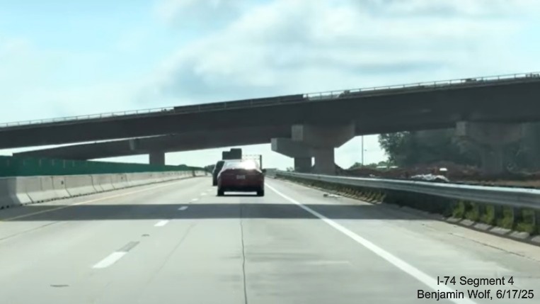 Image of traffic on I-40 East passing under two of the future flyover ramps to
	  the I-74 / Winston-Salem Northern Beltway, screen grab from Benjamin Wolf video, June 2025