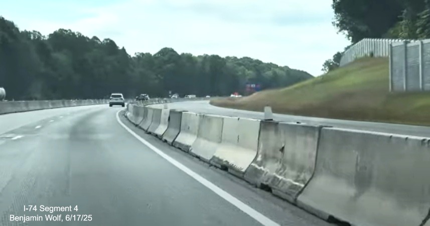 Image of traffic on I-74 East passing completed noise walls after the future I-74 /
	  Winston-Salem Northern Beltway interchange, screen grab from Benjamin Wolf video, June 2025