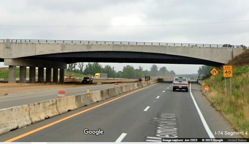 Image of US 52 North roadway paralleling future I-74 West lanes still under construction heading
        under NC 65 bridge as part of the future Winston-Salem Northern Beltway interchange construction project, Google Maps Street View, June 2023