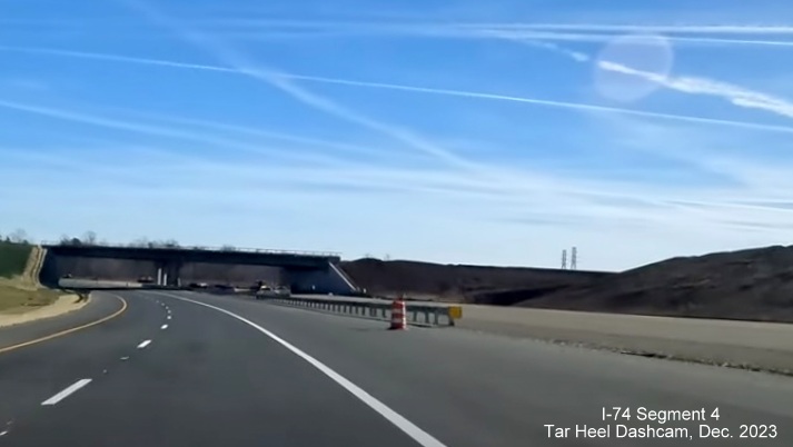 Image of NC 74 (Future I-74) East using future westbound lanes prior to future ramp bridge for
        US 52 South exit, from video by Tar Heel Dashcam, December 2023