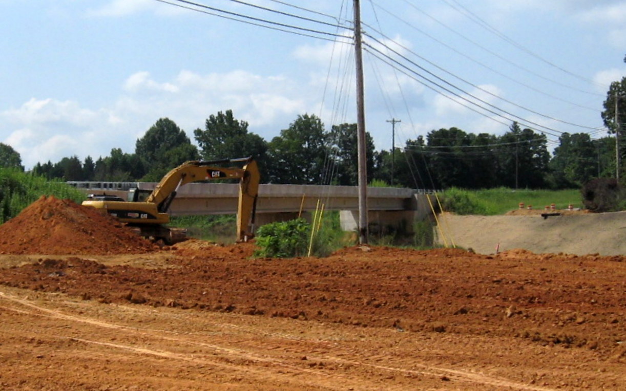 Photo of workers completing the grading around the completed Branson Davis Rd 
Bridge over the future I-74 freeway in Aug. 2012