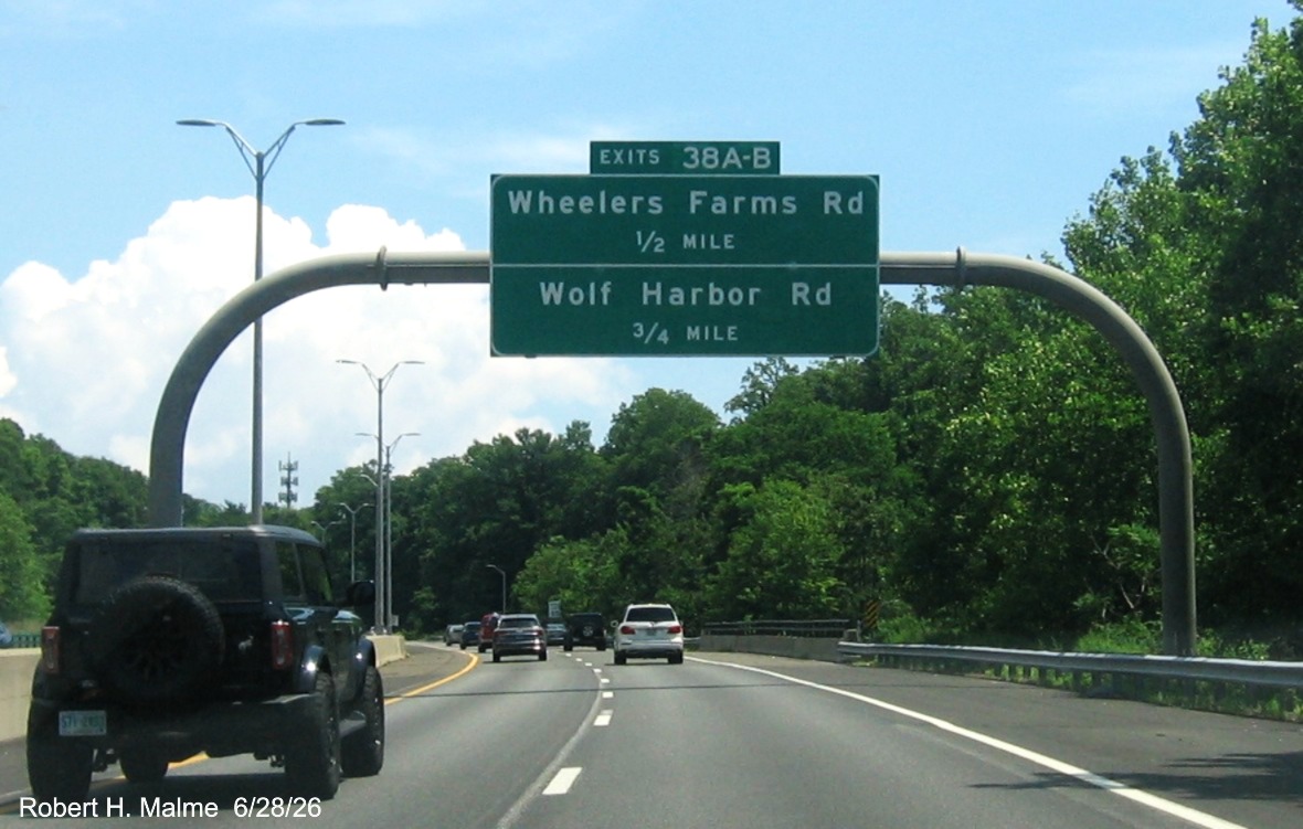 Image of overhead advance signs for the Wheelers Farm Road and Wolf Harbor Road exits, 
 with new milepost based exit numbers on CT 15 North/Cross Parkway in Milford, June 2026