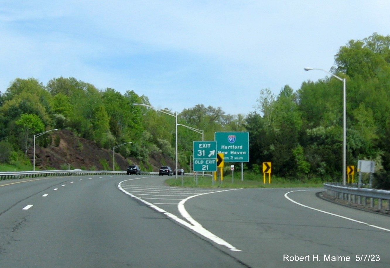 Image of gore sign US 5/CT 15 exit with new milepost based 
        exit numbers and Old Exit 21sign below on CT 9 South in Berlin, May 2023