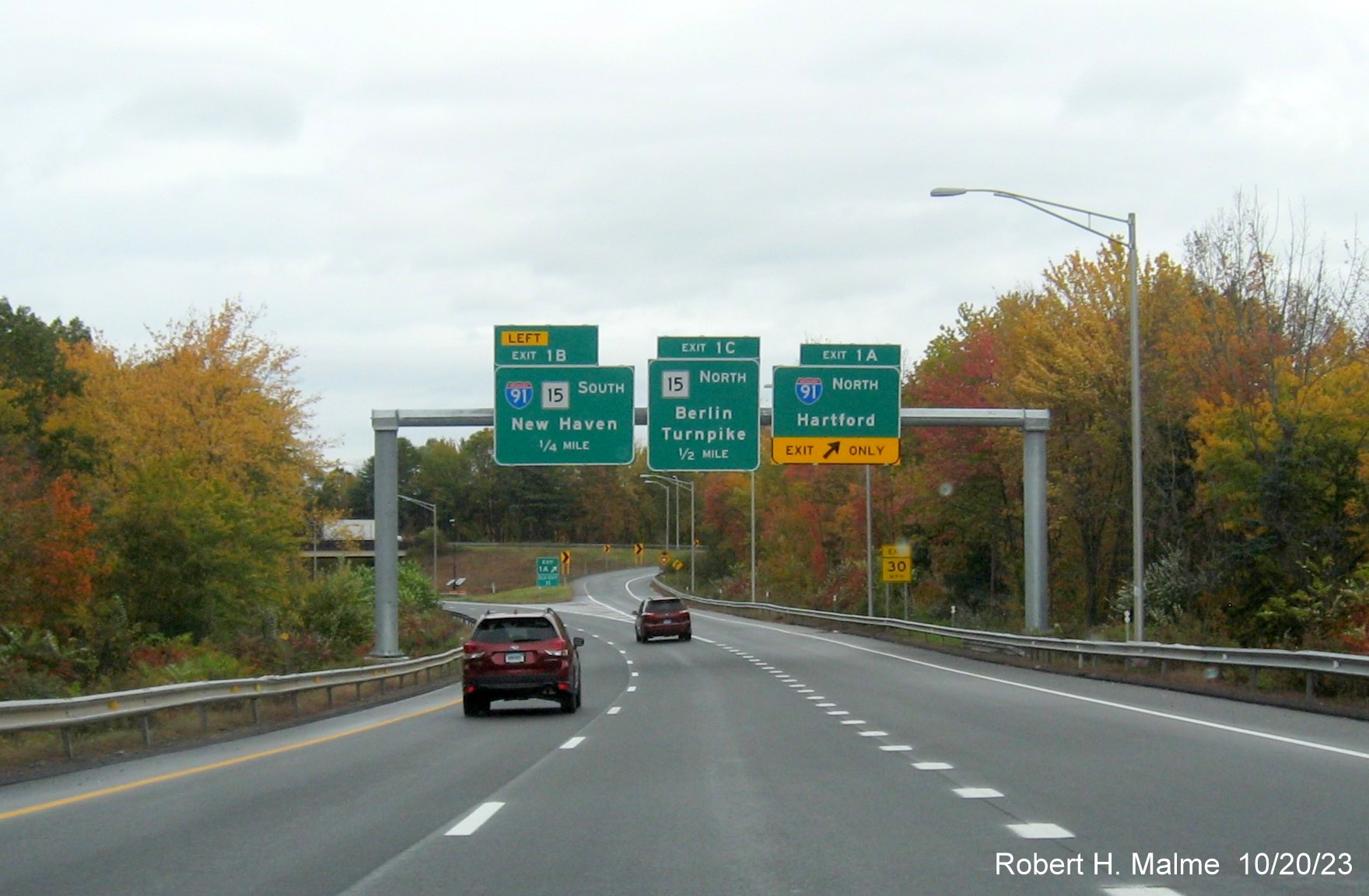 Image of new overhead signs with new milepost based exit number for the I-91/CT 15 exits at the 
        beginning of I-691 West in Meriden, October 2023