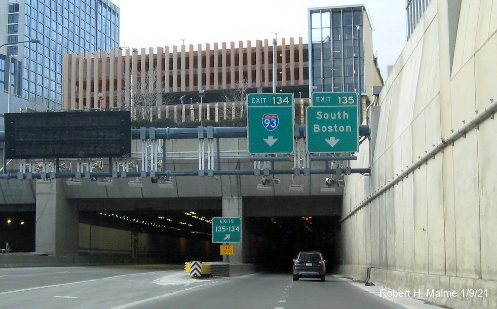Image of overhead ramp sign for I-93 and South Boston Exits with new milepost based exit number and gore sign
                                       with yellow Old exit numbers sign below, January 2021