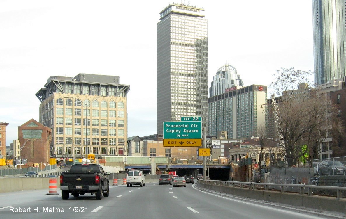 Image of 1/2 Mile advance overhead sign for Prudential Center exit with unchanged sequential exit number but yellow
                                      old exit sign on support post on I-90 East in Boston, January 2021