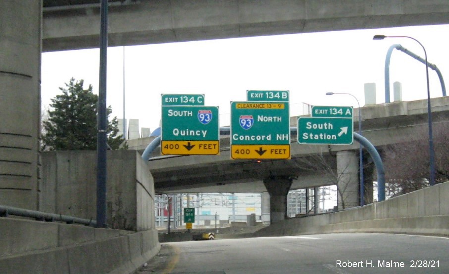Image of overhead ramp signs for I-93 and South Boston exits with new milepost based exit numbers on I-90 
                                         East in Boston, February 2021