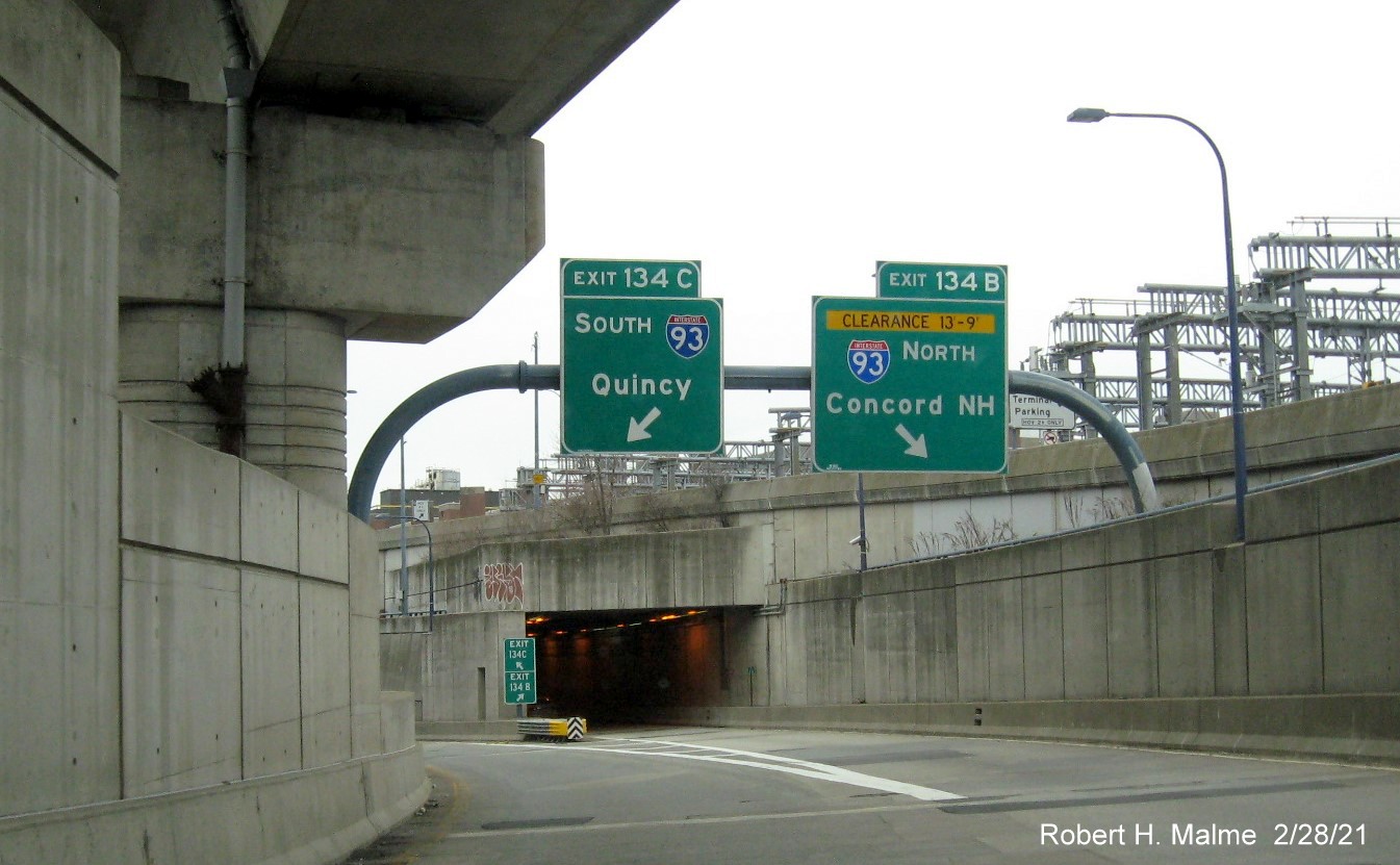 Image of overhead ramp signs for I-93 exits with new milepost based exit numbers on I-90 
                                         East in Boston, February 2021