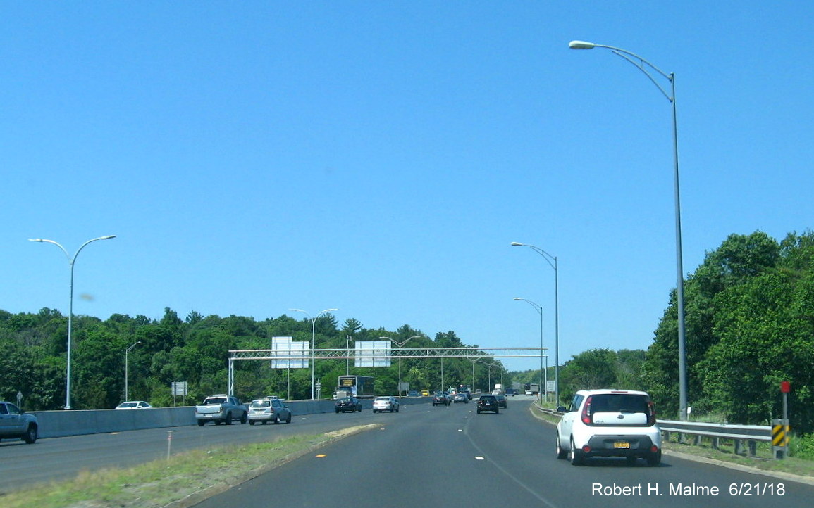 Image of back of newly installed overhead sign gantry over west and eastbound lanes of I-90/Mass Pike in Weston
