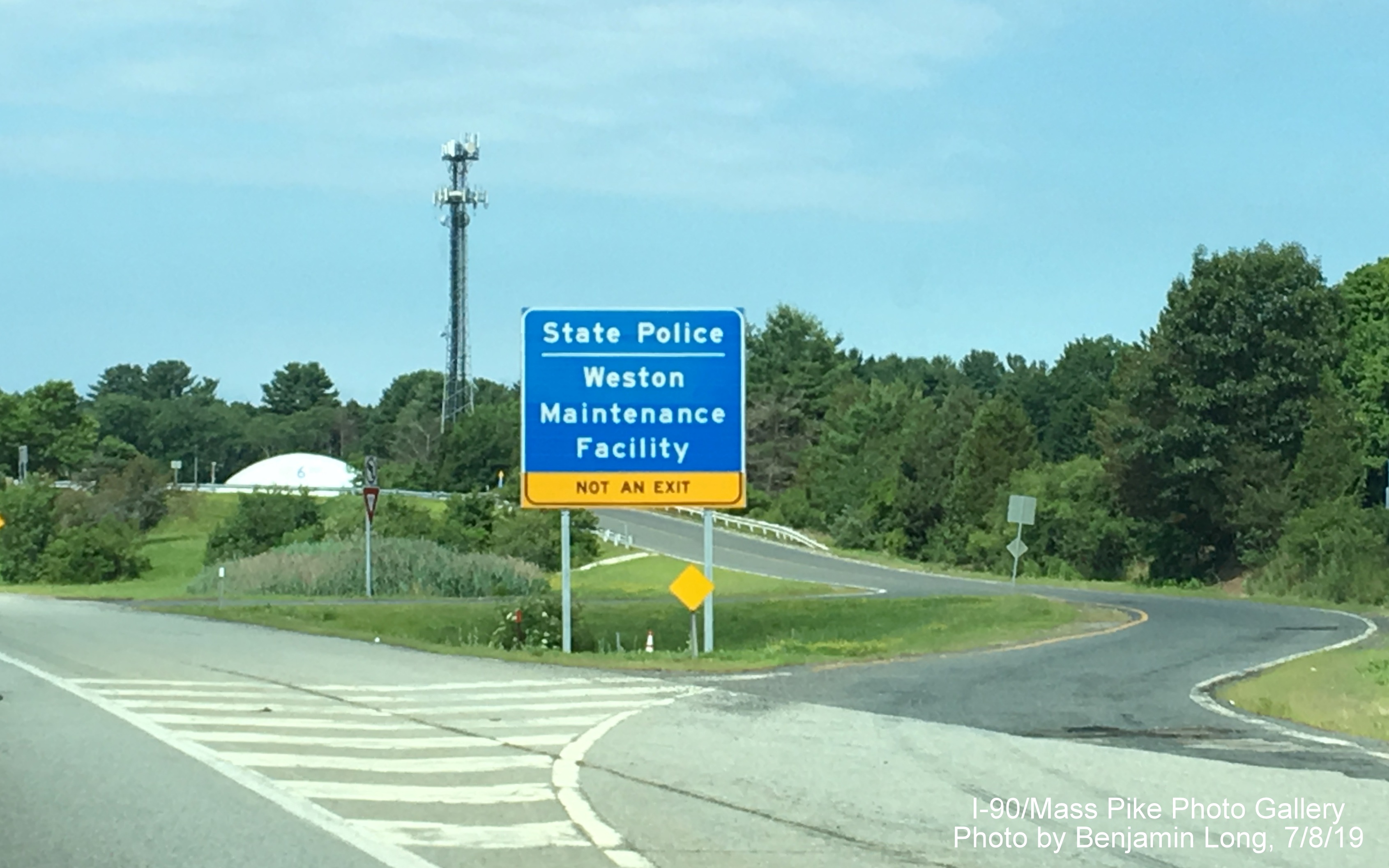 Image of newly placed blue advisory sign for entrance to Weston State Police Barracks/Maintenance
Facility on I-90/Mass Pike West, by Benjamin Long