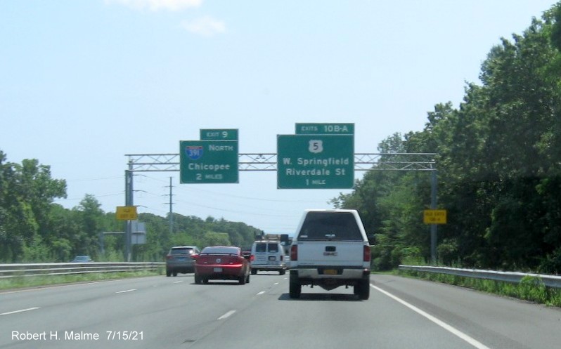 Image of overhead advance signs for I-391 and US 5 exits with new milepost based exit numbers and yellow 
                                         Old Exits 13 A-B and Old Exit 12 advisory sign on right and left supports on I-91 South in West                                          Springfield, July 2021