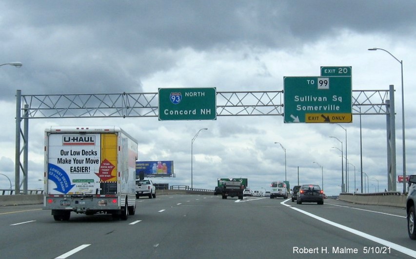 Image of overhead ramp sign for To MA 99 exit with new milepost based 
          exit numbers on I-93 North in Charlestown, May 2021
