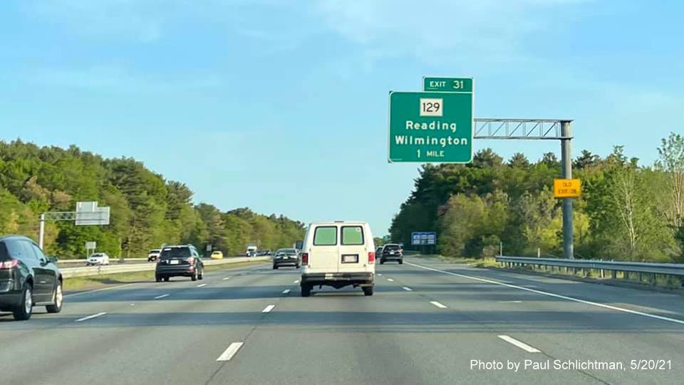 Image of 1 Mile advance sign for MA 129 exit with new milepost based exit number and yellow Old Exit 38 advisory sign on support 
                  on I-93 North in Wilmington, by Paul Schlichtman, May 2021