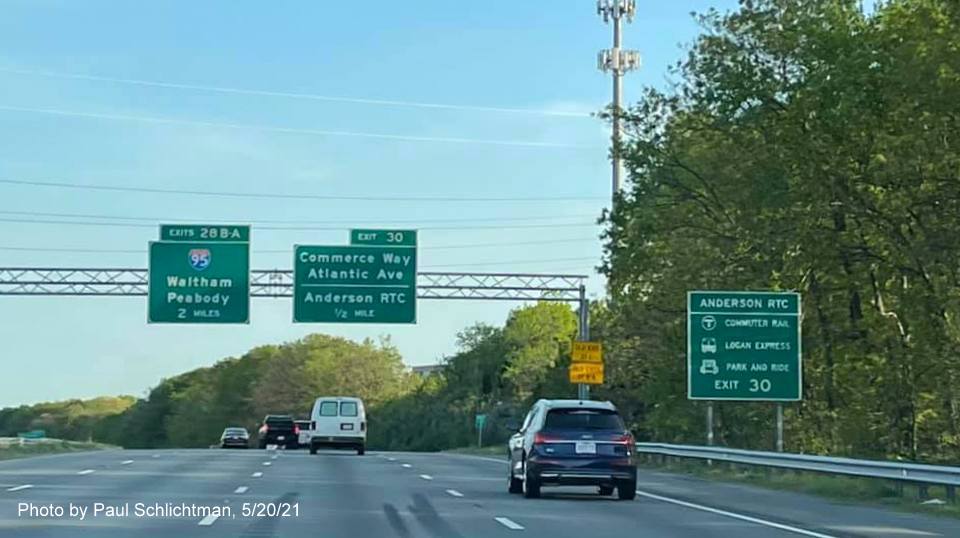 Image of overhead advance signage for I-95/MA 128 and Commerce Way exits with new milepost based exit 
                                            numbers on I-93 South in Woburn, by Paul Schlichtman, May 2021