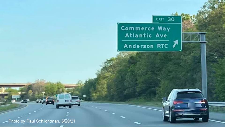 Image of overhead ramp sign for Commerce Way exit with new milepost based exit 
                                            number on I-93 South in Woburn, by Paul Schlichtman, May 2021