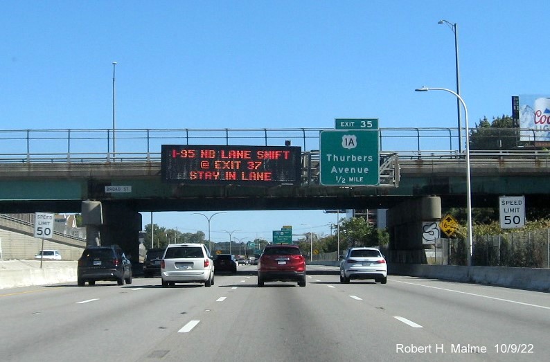 Image of 1/2 mile advance overhead sign for US 1A exit with new milepost based exit number and yellow Old Exit 18 sign above exit tab, on I-95 North in Providence,  October 2022