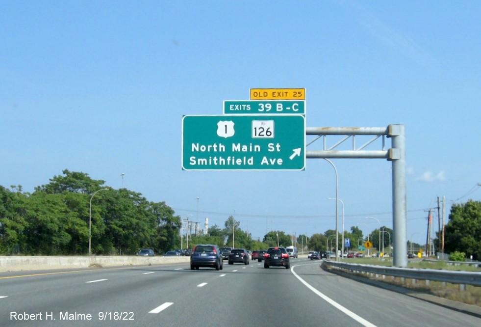 Image of overhead ramp sign for US 1/RI 126 exits with new milepost based exit numbers and Old Exit 25 tab on top
        on I-95 North in Providence, September 2022